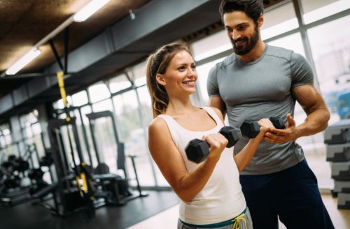 woman lifting dumbbells with trainer
