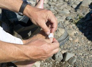 Men putting a bandaid on a blister.