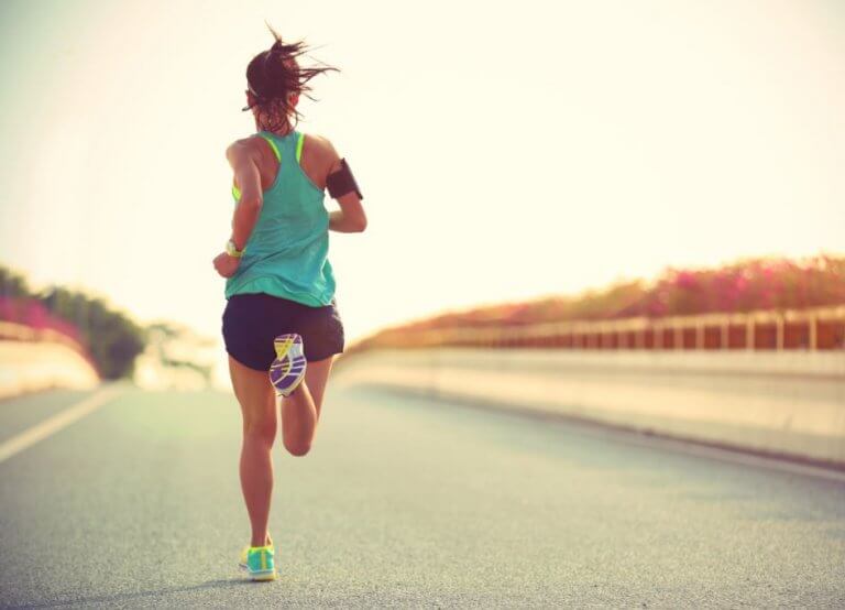 kvinde der løber alene på solskinsrig vej