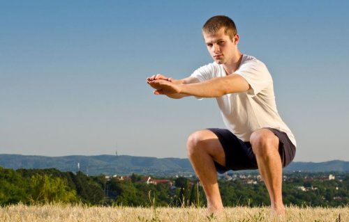 man outside doing squat in sun