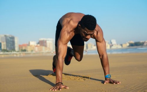 man exercising in sand with fitness watch