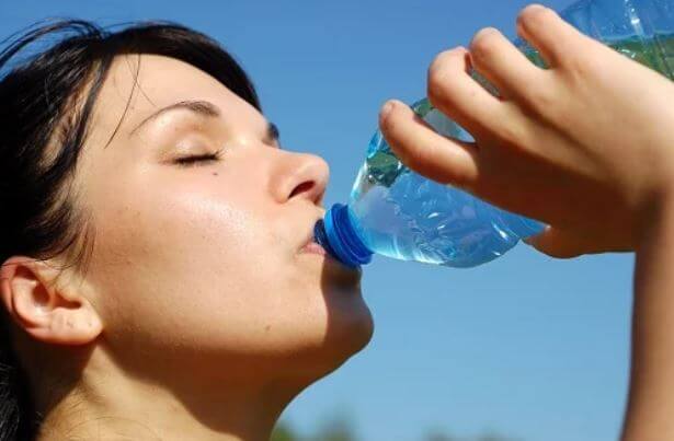 kvinde der drikker vand fra en flaske