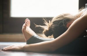 Woman doing the head-to-knee pose.
