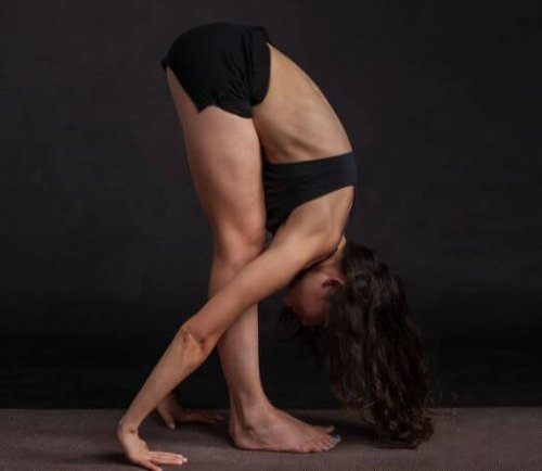 woman on black background doing standing forward bend yoga exercises