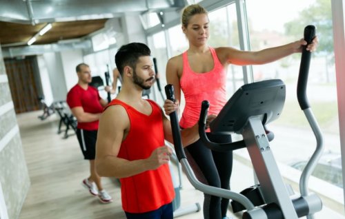 woman on elliptical at gym with trainer slimming down with cardio