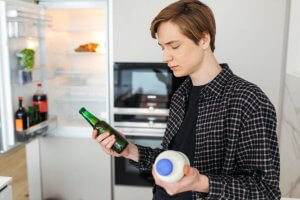 Guy deciding between beer or milk.