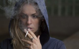 Woman smoking with her hood on.