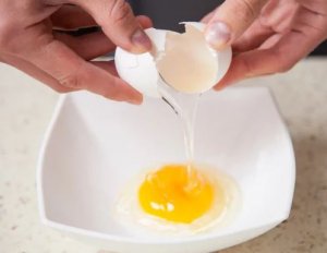 Person taking out yolks of eggs.