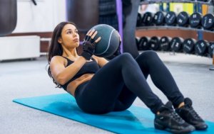 Woman doing sit ups with a medicine ball.