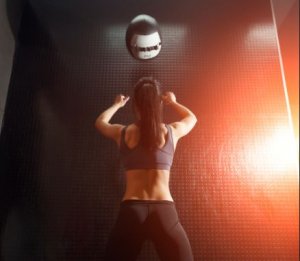Woman throwing a medicine ball against a wall.