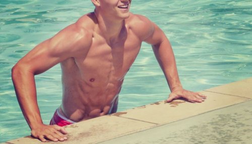 toned man leaning out of outdoor pool
