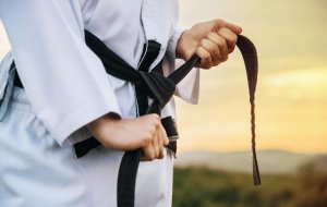 Men adjusting his black judo belt.
