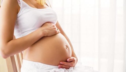 pregnant woman in white holding belly