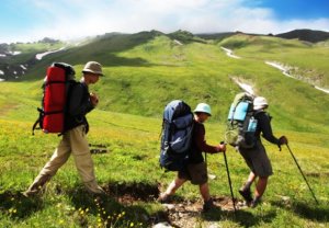 Three men carrying their trekking backpacks.