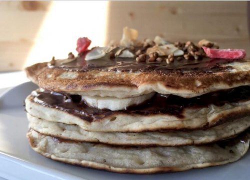 stack of pancakes with chocolate syrup and bananas