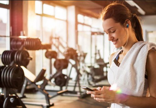 woman smiling looking at phone at the gym