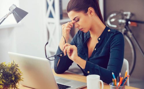 woman rubbing her eyes at work thinking about the psychological aspect of weight loss