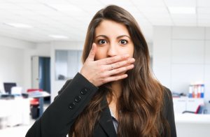 Woman covering her mouth because of Halitosis