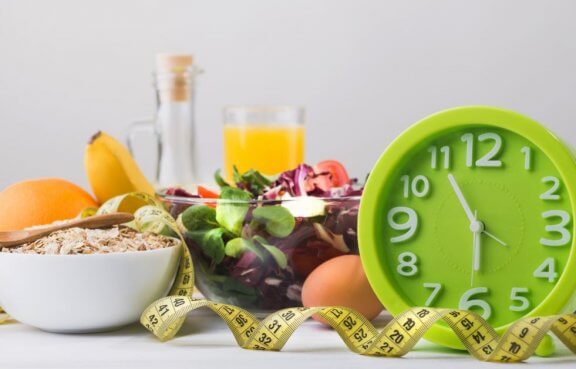 målebånd, mad og ur der ligger på et bord