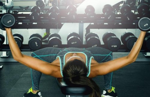 Woman on gym bench chest press
