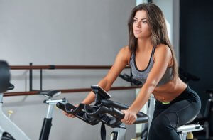 Cardio machines: girl on stationary bicycle.