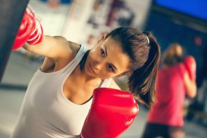 Woman fighting depression by punching heavy bag.