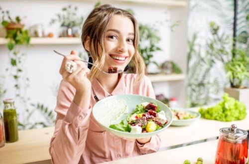 ung, smilende kvinde der spiser en salat