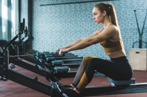 Girl building her back with rowing machine.