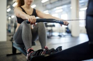 Cardio machines: girl on a rowing machine.