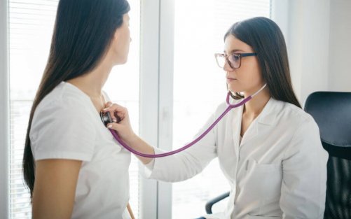 ung kvindelig læge der lytter på en kvindes bryst