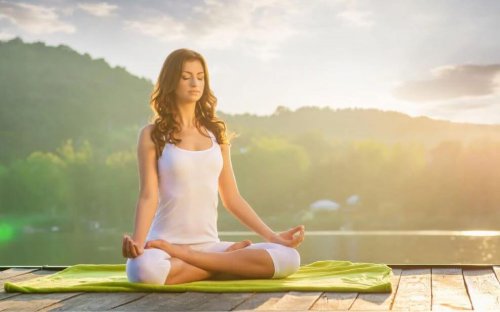Ways to reduce stress woman sitting on dock on lake meditating