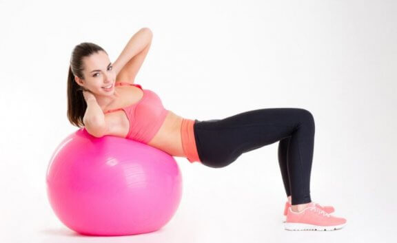kvinde der laver maveøvelse på pink bold
