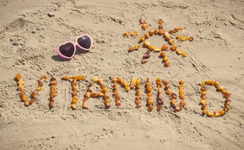 Vitamin D spelled out in sand on beach