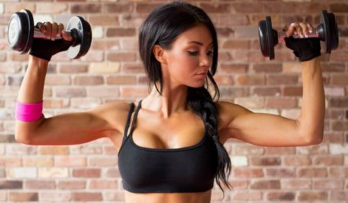 Woman using handweights to train arms in gym female bodybuilding