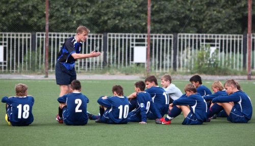 A coach training children on a football team.