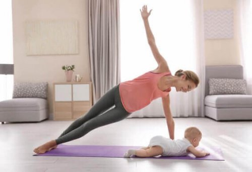 Mother doing yoga next to her infant postpartum exercises