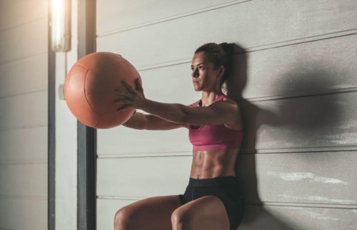 Woman using a weighted ball to do squats against the wall