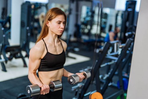 Woman doing bicep curls with dumbbells at gym