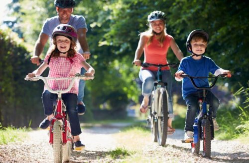 Family riding bikes in a park four member family