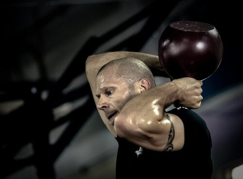 Man swinging kettlebell behind head