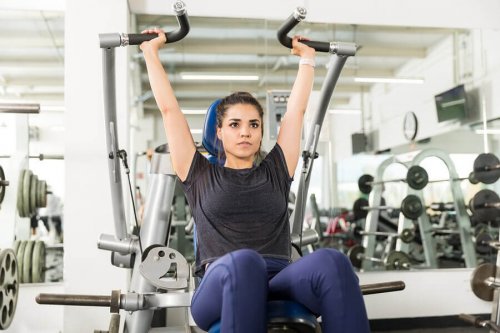 Woman in gym working out on the machines arm press