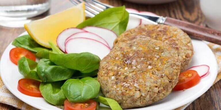 Two lentil burgers next to a green salad
