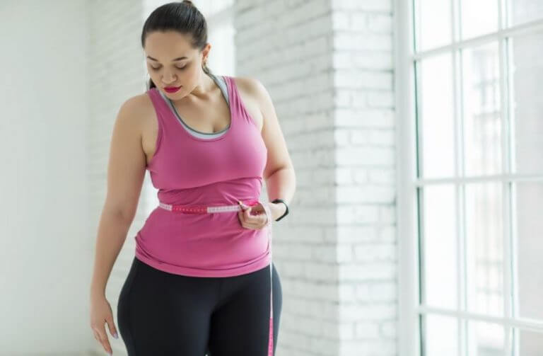 An overweight woman measuring her waist to set proper wieght loss goals