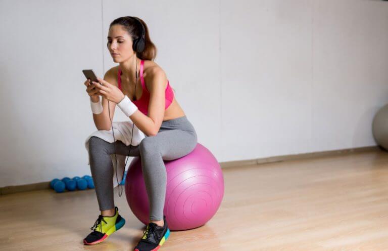 A woman sitting on a fitness ball while taking a rest from her weight training