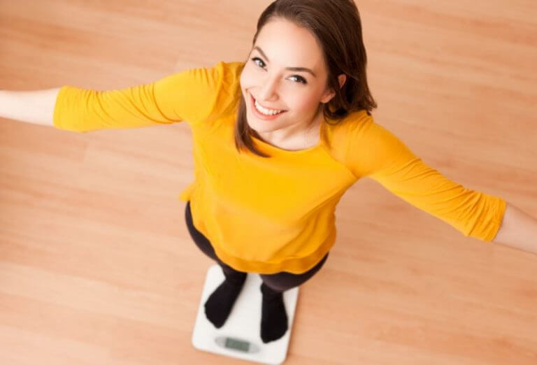A woman standing on top of a scale smiling