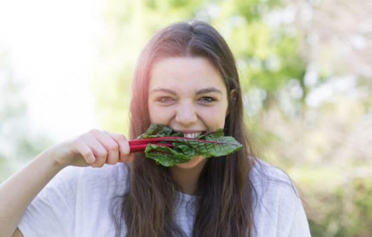 Woman biting into a dark green leaf to get enough iron