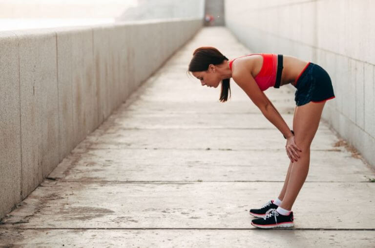 A woman feeling tired after running due to a possible iron deficiency