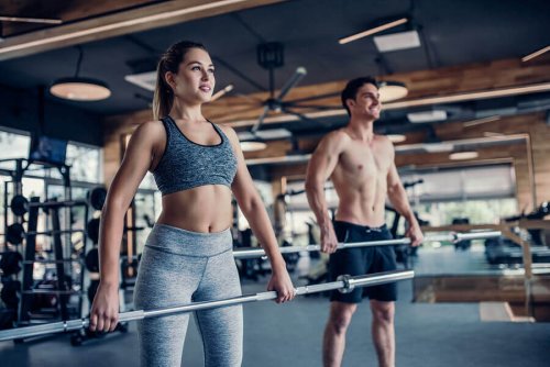 Couple in gym lift bar to work trapezoids