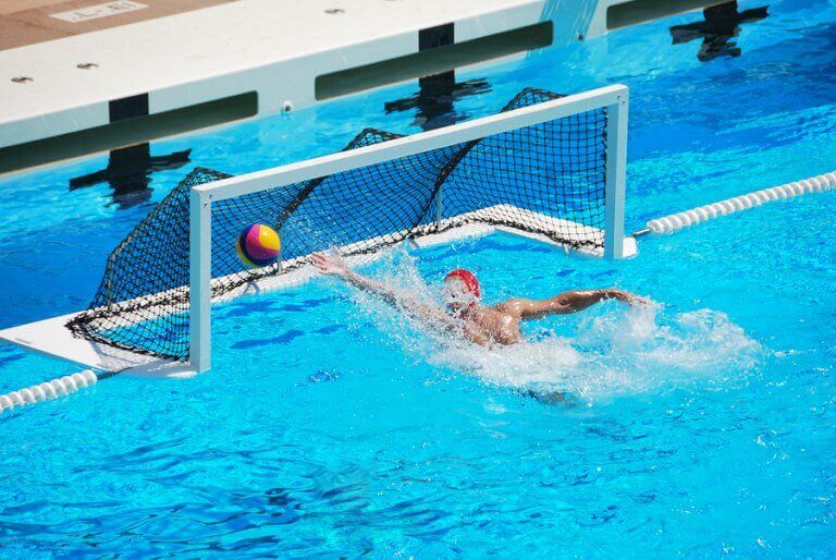 A waterpolo player blocking the ball in a pool