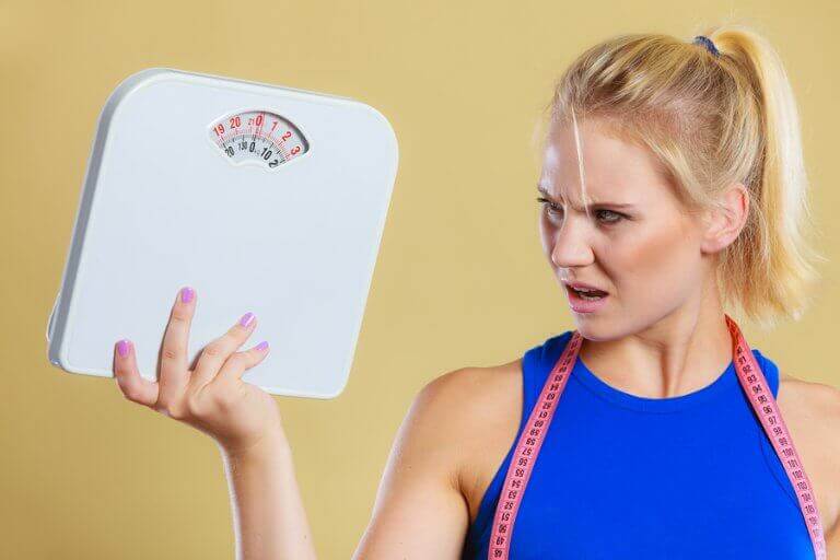 A woman holding a scale and looking at it